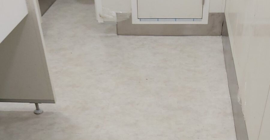 General use bathrooms floor with vinyl tiles & inox skirting board